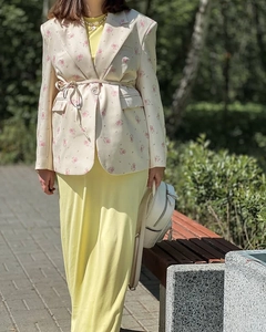 Detail of floral blazer waist tie and print pattern worn with a yellow dress