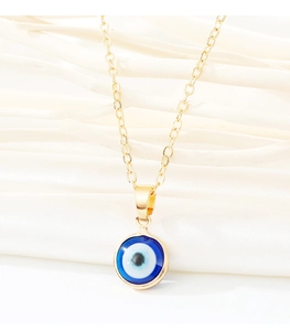 Macro view of a gold-plated evil eye pendant on a delicate chain against white fabric