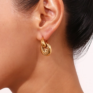 Close-up of chunky gold-plated chain link hoop earrings worn by a female model