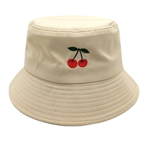 Close-up of the delicate cherry embroidery and texture on the beige bucket hat fabric