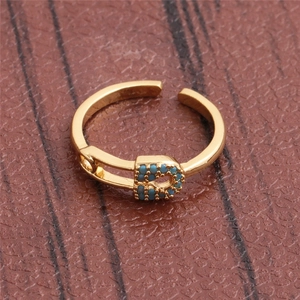 Macro shot of gold paperclip ring with turquoise stones on brown leather background