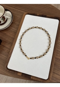 Détail d'un collier de perles vintage avec œil de tigre sur un plateau en bois