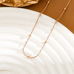 Minimalist 18K gold-plated stainless steel snake chain necklace with smooth beads on a display