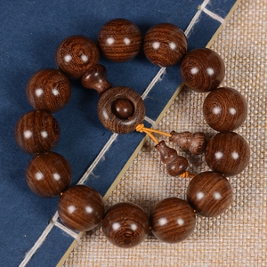 Macro detail of sandalwood prayer beads with gourd pendant on a vintage book background