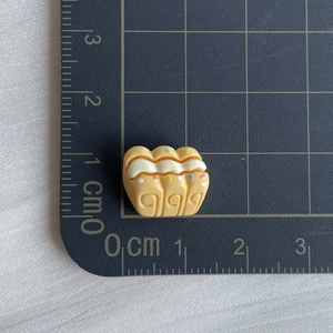 Macro shot of a mini resin croissant accessory with cream topping on a metric scale mat