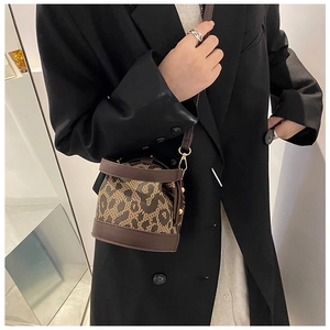 Detail view of a vintage leopard print bucket bag styled with a professional black blazer