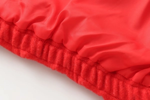 Detailed close-up of the bright red bomber jacket featuring a ribbed elastic hem and soft lining