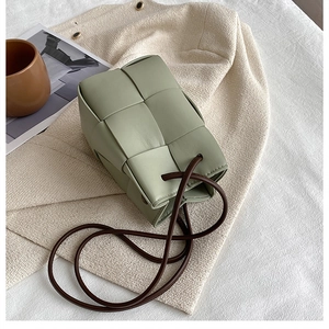 Close-up of green woven bucket bag with intricate leather texture and brown strap