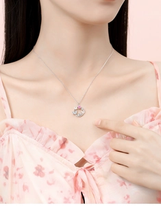 Detailed close-up of a silver butterfly ring pendant with pink heart gemstone on neck