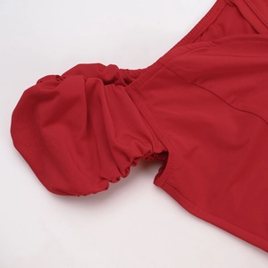Détail d'une robe en satin rouge avec manches bouffantes plissées et coutures précises