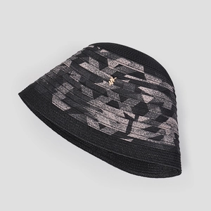 Détail d'un chapeau cloche noir tressé avec des motifs géométriques et un logo doré