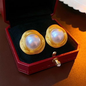 Detailed view of vintage gold pearl earrings placed in a luxurious red jewelry box