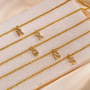 Detailed view of gold titanium chains with micro-pave letter pendants R, X, G, N, S