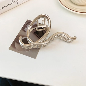 Detailed view of irregular geometric silver hair claw clip on a minimalist white table