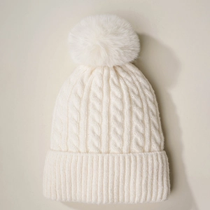 Cream white cable knit beanie hat with large faux fur pompom for winter outdoor warmth