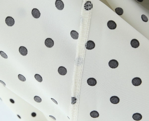 Macro shot of polka dot fabric texture with high-quality lace trim and fine stitching