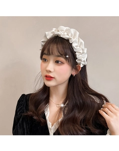 Détail d'un serre-tête en satin plissé blanc sur modèle au style rétro français chic