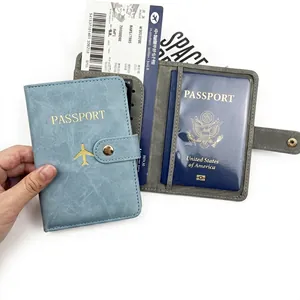 Detalle de fundas para pasaporte de cuero PU azul y gris con logo de avión dorado y botón