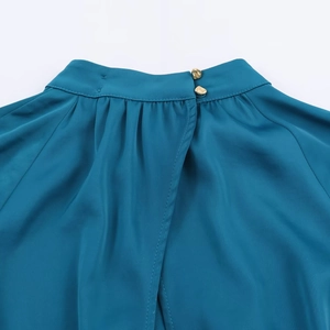 Détail de l'encolure de la robe midi en satin bleu paon avec boutons dorés élégants