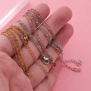 Minimalist stainless steel bead chains in gold, silver, and rose gold on a hand