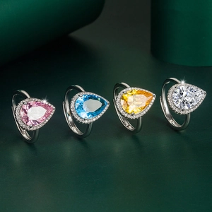 Detail view of four pear-shaped drop rings with pink, blue, yellow and clear zircons