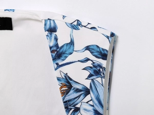Close-up of the shoulder and neckline showing the blue floral print on white fabric