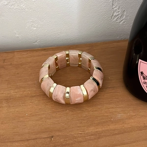 Détail d'un bracelet en résine marbrée rose avec accents métalliques dorés