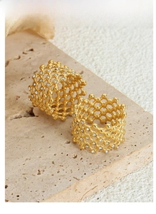 Macro shot of 18K gold plated mesh rings with crystals on a textured stone tray
