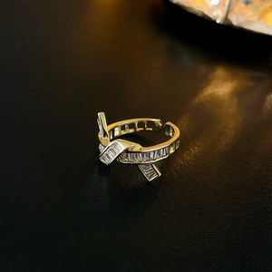 Macro shot of gold plated open ring with ribbon knot design and baguette cubic zirconia
