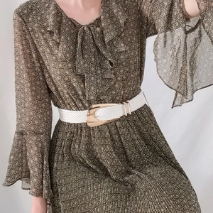 Detail of a woven white belt with a large polished gold metal buckle on a floral dress