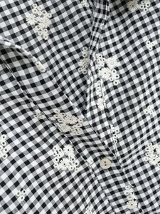 Détail d'une chemise vichy avec broderie florale blanche et texture de bouton nacré