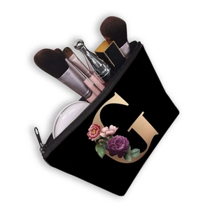 Black dumpling makeup bag with golden letter G and floral print holding brushes