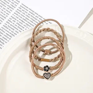 Detail view of earth-toned elastic hair ties with heart and flower charms in a ceramic tray