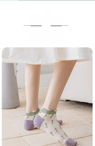 Detailed view of floral socks with tulip patterns and ruffled edges worn by a model