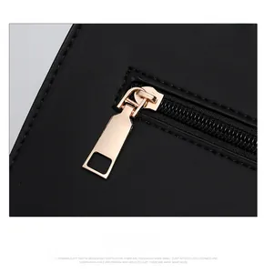 Close-up of golden metal zipper hardware on black leather texture of a shoulder bag