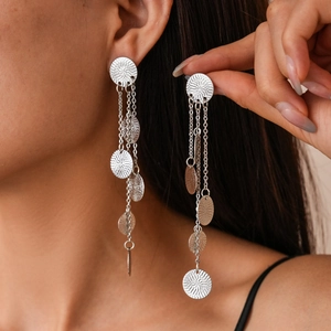 Silver fringe earrings with circular textures on metallic disks worn by a model