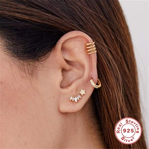 Vue macro de la boucle d'oreille et des clous en argent 925 avec zircons sur l'oreille