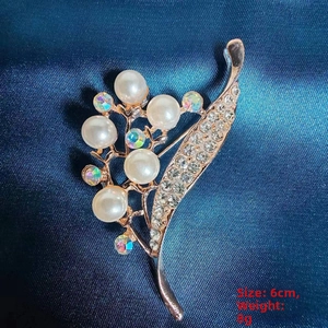 Close-up of camellia brooch with white pearls and AB rhinestones on blue silk, 6cm size