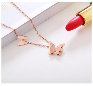 Macro shot of rose gold butterfly necklace with matte and polished finishes on dual pendants