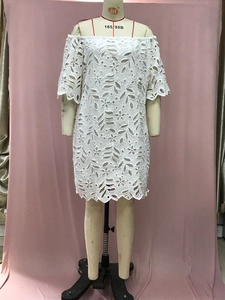 Detailansicht des weißen Spitzenmusters mit floralen Aussparungen am schulterfreien Kleid