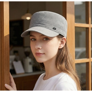 Close-up detail of a grey flat top military style sun cap worn by a model