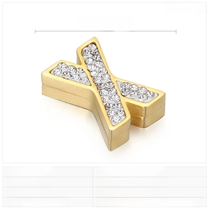 Macro detail of gold stainless steel X-shape pendant with sparkling rhinestone inlay