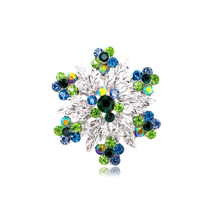 Silver snowflake brooch with blue and green rhinestones on a white background