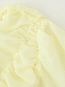 Detailed macro view of pleated light yellow chiffon fabric texture and airy material