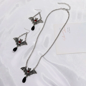 Detail of silver bat necklace and earrings with red gems and black teardrop pendants