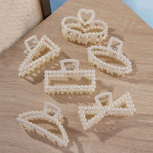 Elegant pearl hair claw clip set for women with various shapes on wood background