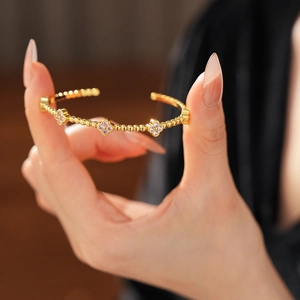 Dettaglio macro del bracciale placcato oro 18k con fiori e zirconi viola incastonati