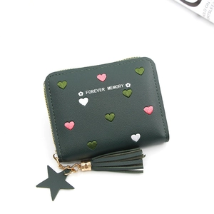 Detail of dark green coin purse featuring heart embroidery and tassel star charm
