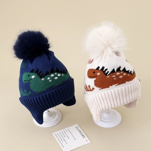 Detail of dinosaur jacquard knit patterns and soft faux fur pom-poms on winter earflap hats