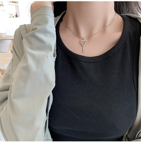 Gros plan d'un collier pendentif clé en forme de cœur argenté avec cristaux étincelants